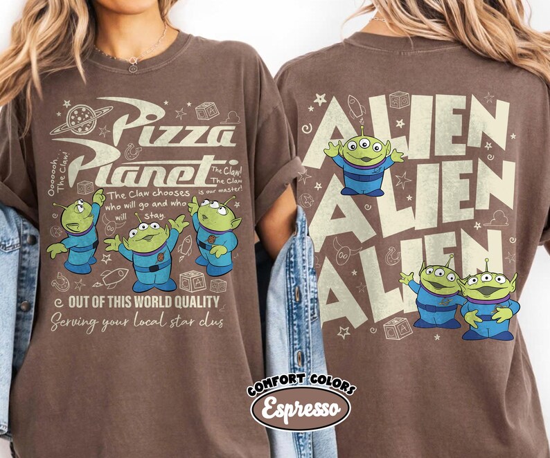 May include: Brown t-shirt with the Pizza Planet logo and three green aliens in blue suits. The text reads "The Claw chooses who will go and who will stay." The back of the shirt says "Alien" multiple times.