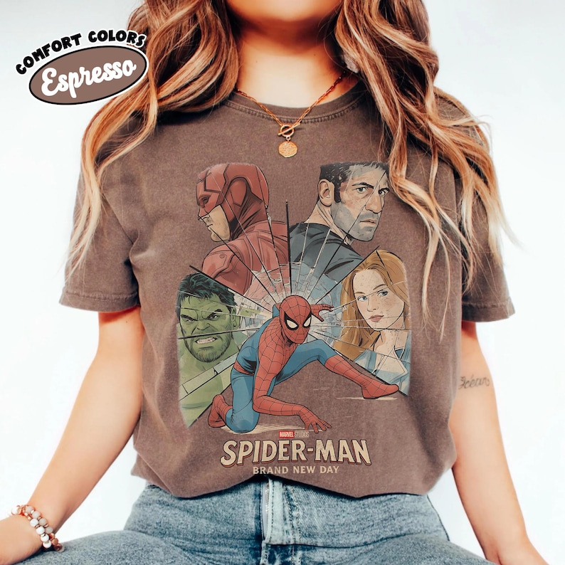 May include: Espresso-colored t-shirt featuring a graphic of Spider-Man and other Marvel characters. The design includes the text "SPIDER-MAN BRAND NEW DAY". The shirt has a vintage look with the words "COMFORT COLORS" and "Espresso" in a circular design.