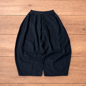 May include: Black denim trousers with a wide, loose cut. The trousers feature a button and zip fastening, with pockets and belt loops. The fabric looks to be a medium-weight denim, and the trousers are displayed flat on a wooden surface.