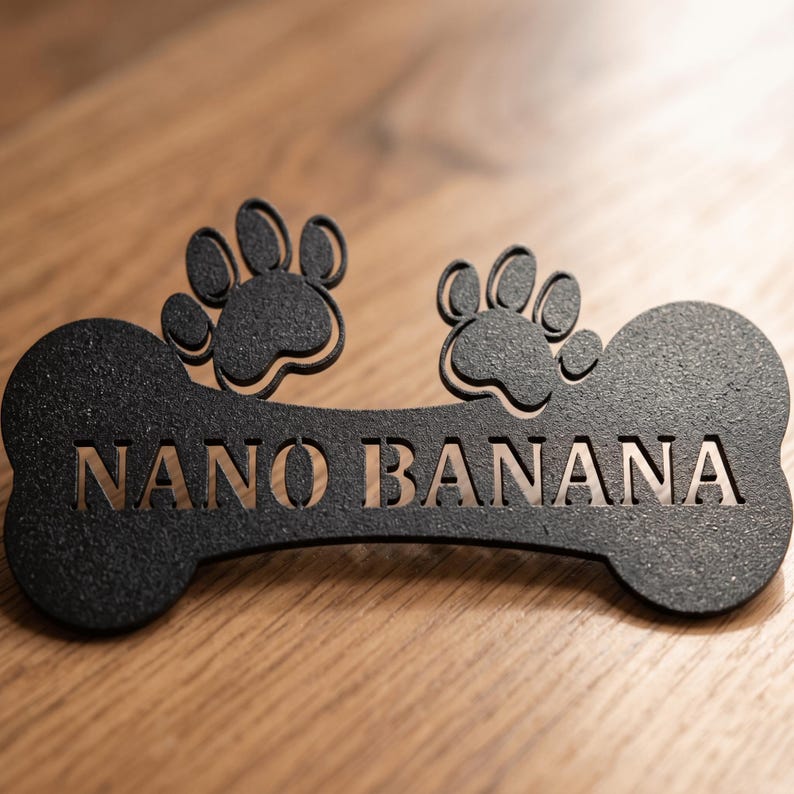 May include: Black metal dog bone-shaped sign with the name "NANO BANANA" cut out. Two paw prints are above the bone. The sign is on a wooden surface.