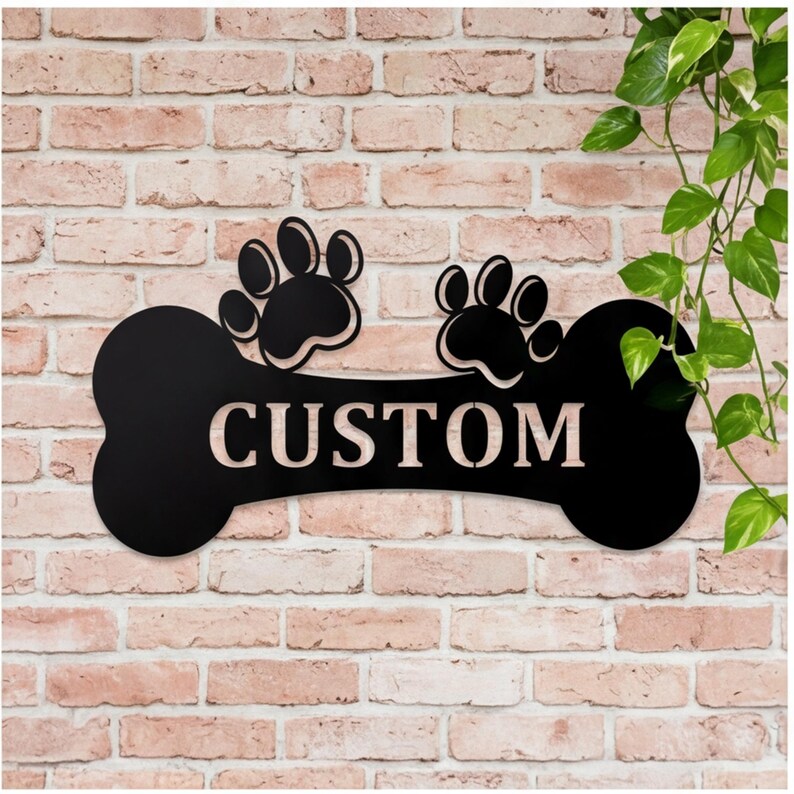 May include: Black metal dog bone-shaped sign with two paw prints and the word "CUSTOM" in white. The sign is mounted on a brick wall, with green leafy vines in the background.