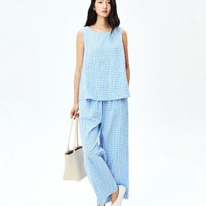 May include: A sleeveless top and wide-leg trousers set featuring a light blue and white gingham check pattern. The outfit is paired with white flat shoes and a plain beige tote bag, creating a coordinated ensemble with a consistent checkered print.