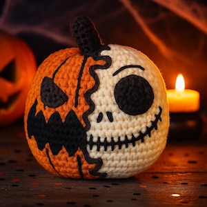 Może przedstawiać: Szydełkowa dynia na Halloween z podzielonym wzorem. Jedna połowa jest pomarańczowa z wyrzeźbioną twarzą jack-o'-lantern, druga połowa jest biała z twarzą czaszki. Dynia ma czarną łodygę i jest ustawiona na ciemnym tle.