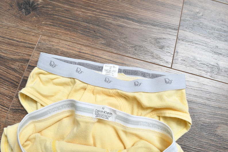 Pu&ograve; includere: Due paia di biancheria intima gialla con elastico in vita. Un paio presenta il logo "Christian Dior", e l'altro ha il logo "Calvin Klein". La biancheria intima &egrave; realizzata in un materiale morbido e confortevole.