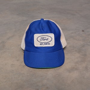 May include: A blue and white trucker hat with a white patch that says "Ford Atlanta" in blue embroidery.