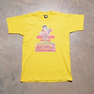 May include: Yellow t-shirt featuring a graphic of a person skateboarding and the text "Asphalt Animal".