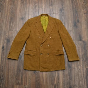 May include: A double-breasted blazer in a textured mustard-brown fabric featuring a notched lapel, two flap pockets, and a bright chartreuse lining. The sleeves are finished with two buttons at each cuff, and the front closes with four buttons.