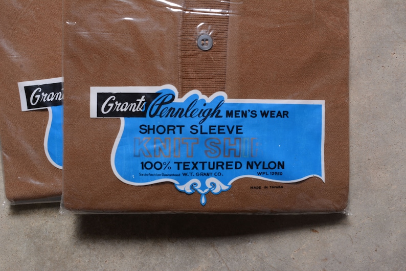 May include: Two brown short-sleeved shirts in plastic packaging. The label reads "Grants Pennleigh Men's Wear Short Sleeve Knit Shirt 100% Textured Nylon Satisfaction Guaranteed W.T. Grant Co. WPL 12950 Made in Taiwan."