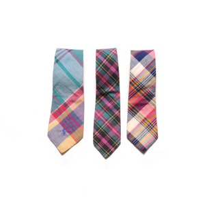 May include: Three plaid neckties in different colour combinations. The neckties are blue, green, and pink with white accents.