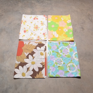 Könnte beinhalten: Vier Stoffquadrate mit Blumenmustern. Die Quadrate sind in den Farben Gelb, Blau, Braun und Weiß.