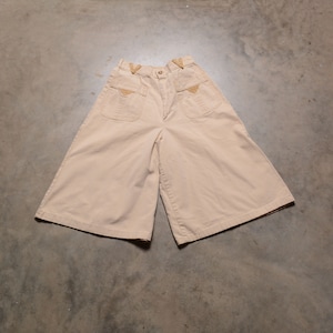 Peut inclure: Un short large beige clair à jambes larges avec deux grandes poches plaquées à l'avant. Les poches ont une bordure marron.