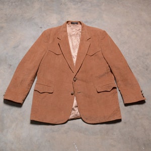 May include: A brown corduroy blazer with a single button closure and two flap pockets on the chest.