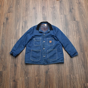 May include: A blue denim jacket with a black corduroy collar. The jacket has four front pockets, a button-up closure, and a small logo patch on the chest. The interior lining is a plaid pattern.
