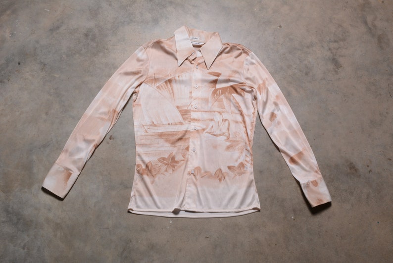 May include: A long-sleeved, button-up shirt with a light brown background and a brown print of palm trees and a beach scene.