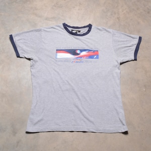 Puede incluir: Camiseta gris con cuello de canalé azul y negro. La camiseta presenta un estampado gráfico de un diseño rojo, blanco y azul con el texto "Paul Tracy's Exhibition Grand Prix 1998", "Exhibition Australia" y "Grand Prix", y un logotipo de "Shell Advance".