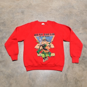 Könnte beinhalten: Roter Pullover mit einer Comic-Illustration eines Soldaten, der eine Waffe hält. Der Text "Hunt Tough or Go Home" ist auf dem Pullover aufgedruckt.