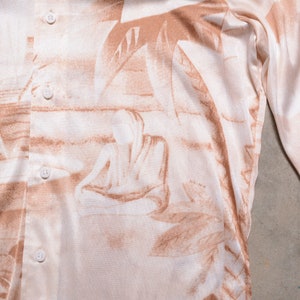 May include: A long-sleeved shirt with a beige background and a brown abstract print. The shirt has a button-up front and a relaxed fit.