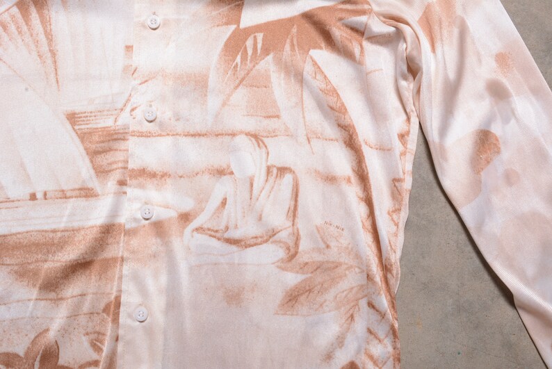 May include: A long-sleeved shirt with a beige background and a brown abstract print. The shirt has a button-up front and a relaxed fit.