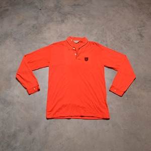 May include: A long-sleeved, bright orange polo shirt with a black button closure and a small black embroidered logo on the chest.