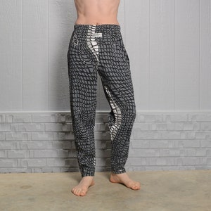 May include: Black and white patterned pants with a white stripe down the side. The pants have a drawstring waist and a relaxed fit.