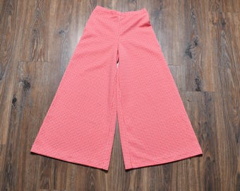 Puede incluir: Pantalones de pernera ancha con estampado de cuadros vichy rojos y blancos. Los pantalones de cintura alta tienen una pernera acampanada. La tela presenta un pequeño diseño de cuadros espaciados uniformemente. Los pantalones están hechos de un material ligero, adecuado para climas cálidos.