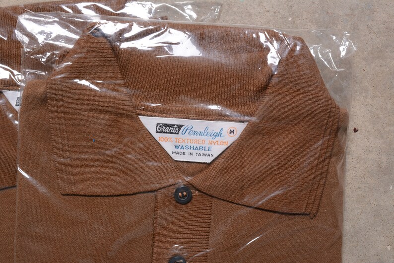 May include: A brown polo shirt with a white label that reads "Grants Pennleigh 100% Textured Nylon Washable Made in Taiwan" and a size "M".