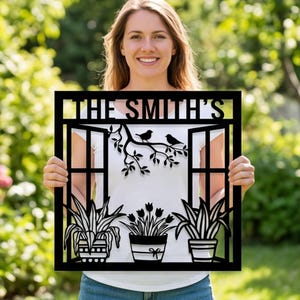 May include: Black metal wall art featuring a window design with the text "THE SMITH'S". The artwork includes a branch with two birds, and potted plants. The design is suitable for indoor or outdoor display.