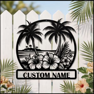 May include: Black metal sign featuring a tropical scene with palm trees, hibiscus flowers, and an island. The sign has a circular design with a rectangular space at the bottom that reads "CUSTOM NAME". The sign is mounted on a white picket fence.