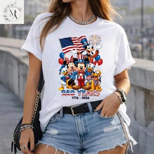 A woman wearing a white t-shirt with a graphic of Disney characters and fireworks, along with the text "250 YEARS 1776-2026".