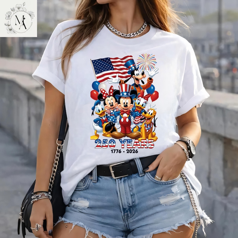 A woman wearing a white t-shirt with a graphic of Disney characters and fireworks, along with the text "250 YEARS 1776-2026".