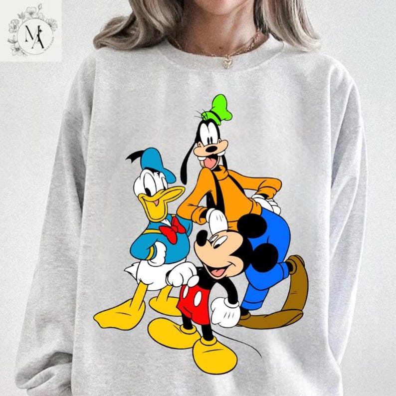 A person wearing a gray sweatshirt with a graphic of Disney characters, including Mickey Mouse, Donald Duck, and Goofy.