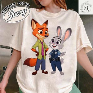 A person wearing a white t-shirt with a cartoon image of a fox and a rabbit, both dressed in police uniforms.