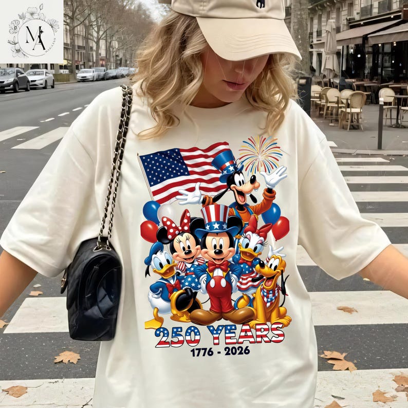 A woman wearing a white t-shirt with a graphic of Disney characters and an American flag, standing on a city street.