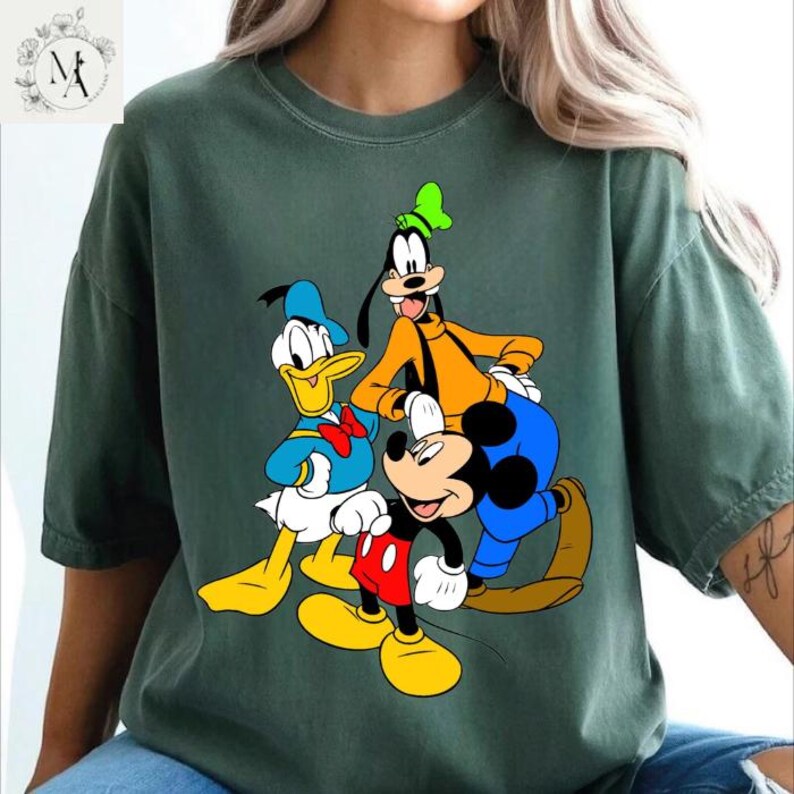 A green t-shirt with a graphic design featuring Disney characters Mickey Mouse, Donald Duck, and Goofy.