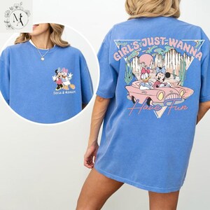 A woman wearing a blue t-shirt with a cartoon character and text printed on it.