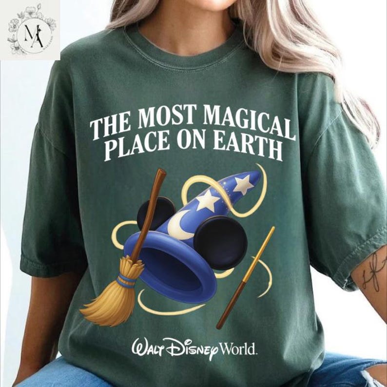 A green t-shirt with a graphic design featuring a wizard's hat, broom, and wand, along with the text "The most magical place on earth" and the Walt Disney World logo.