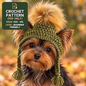 May include: A crochet pattern PDF for a green pet hat with a large brown pom-pom on top and two braided ear flaps with tassels. The text reads: CROCHET PATTERN (PDF ONLY) SIZES: XXS - XXL LEVEL: BEGINNER FRIENDLY.