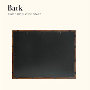 May include: The reverse side of a rectangular photo display pinboard with a dark brown wooden frame. The pinboard features a black backing and metal clips for hanging. The text "Back" and "PHOTO DISPLAY PINBOARD" are at the top.