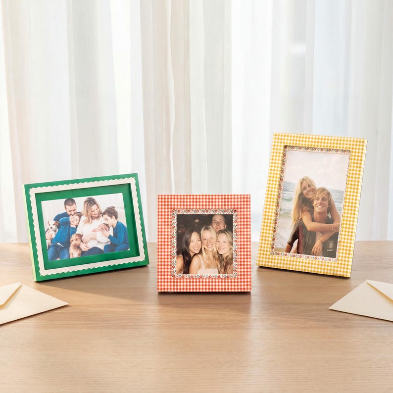 May include: Three picture frames displayed on a surface. The left frame is green with a scalloped edge. The center frame is square with a red and white gingham pattern. The right frame is rectangular with a yellow and white gingham pattern.