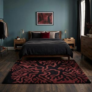 May include: A rectangular area rug featuring a black base with a raised, textured pattern of deep red, organic, branching shapes that resemble coral or root systems, covering the entire surface of the floor in front of a wooden bed frame.