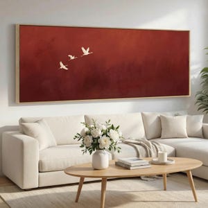 May include: A rectangular wall art piece with a wooden frame. The artwork features three white birds in flight against a deep red background. The birds are depicted in a minimalist style, creating a sense of movement and serenity.