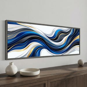 May include: A rectangular wall art piece featuring a horizontal abstract design with flowing, wavy lines in shades of deep blue, charcoal gray, white, and metallic gold. The artwork is enclosed in a dark gray frame and mounted on a wall.
