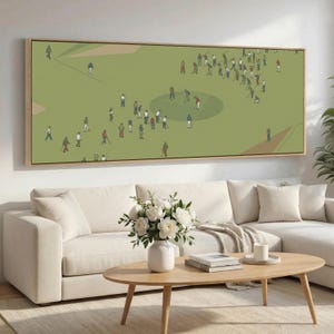 May include: A framed art print depicting a golf course scene with numerous figures in various poses. The artwork features a green field with a circular area and several players. The figures are dressed in a variety of colors, and the frame is a light brown.
