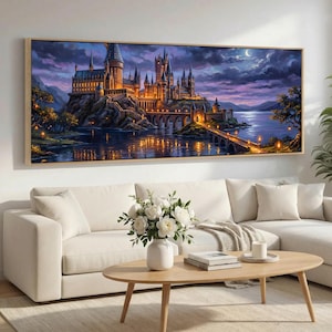 May include: A framed painting depicts a castle at night, illuminated by warm lights. The castle sits on a rocky island, connected by a bridge over a lake. The sky transitions from dark blue to purple, with a crescent moon visible.
