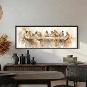 K&ouml;nnte beinhalten: Aquarellmalerei des Letzten Abendmahls in einem schwarzen Rahmen. Das Kunstwerk zeigt Figuren, die um eine lange Tafel sitzen, in ged&auml;mpften T&ouml;nen von Beige, Braun und Grau. Das Gem&auml;lde h&auml;ngt &uuml;ber einem Holzschrank.