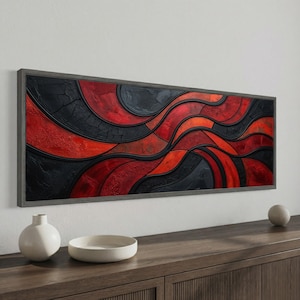 May include: Abstract wall art with a textured design in red and black, framed in grey. The artwork has a wavy pattern, creating a dynamic visual effect. The piece is displayed above a wooden cabinet with decorative items.