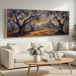 May include: A framed landscape painting depicts a path leading to a golden-domed building, framed by large trees. The artwork features warm earth tones and cool blues, creating a serene and inviting scene. The painting is displayed above a white sofa.