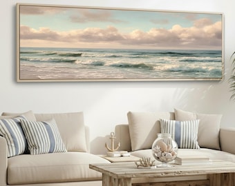May include: A rectangular framed canvas print depicts a serene ocean scene. The artwork showcases a light blue sky with fluffy, pale pink clouds above the turquoise waves. The painting is displayed above a beige sofa with striped pillows.