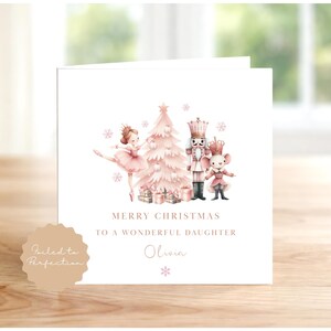 Peut inclure: Une carte de vœux carrée blanche illustrée d'un sapin de Noël rose, d'une ballerine, d'un casse-noisette et d'une souris. Le texte indique MERRY CHRISTMAS TO A WONDERFUL DAUGHTER et le prénom Olivia. Un sceau beige porte Foiled to Perfection.