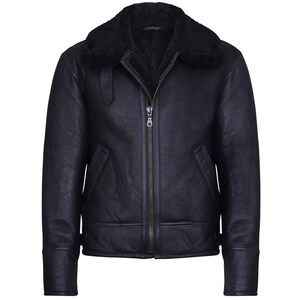 May include: A black leather jacket with a shearling collar. The jacket features a front zipper closure, two side pockets, and a buckled strap detail on the left shoulder. The sleeves have a cuff detail. The jacket is a classic outerwear piece.
